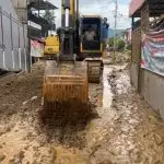 Excavator mengeruk lumpur yang terbawa banjir