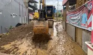 Excavator mengeruk lumpur yang terbawa banjir